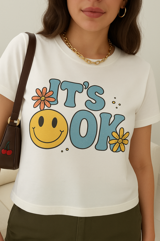 Person wearing a white t-shirt with a smiley face and 'It's OK' text design.